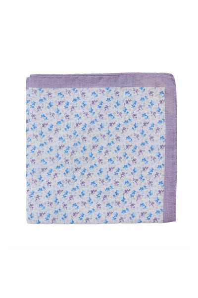 The Parisian Ditsy Linen Pocket Square by Parisian features a white background with small blue and purple floral details and a solid lavender border, shown folded on a white surface.