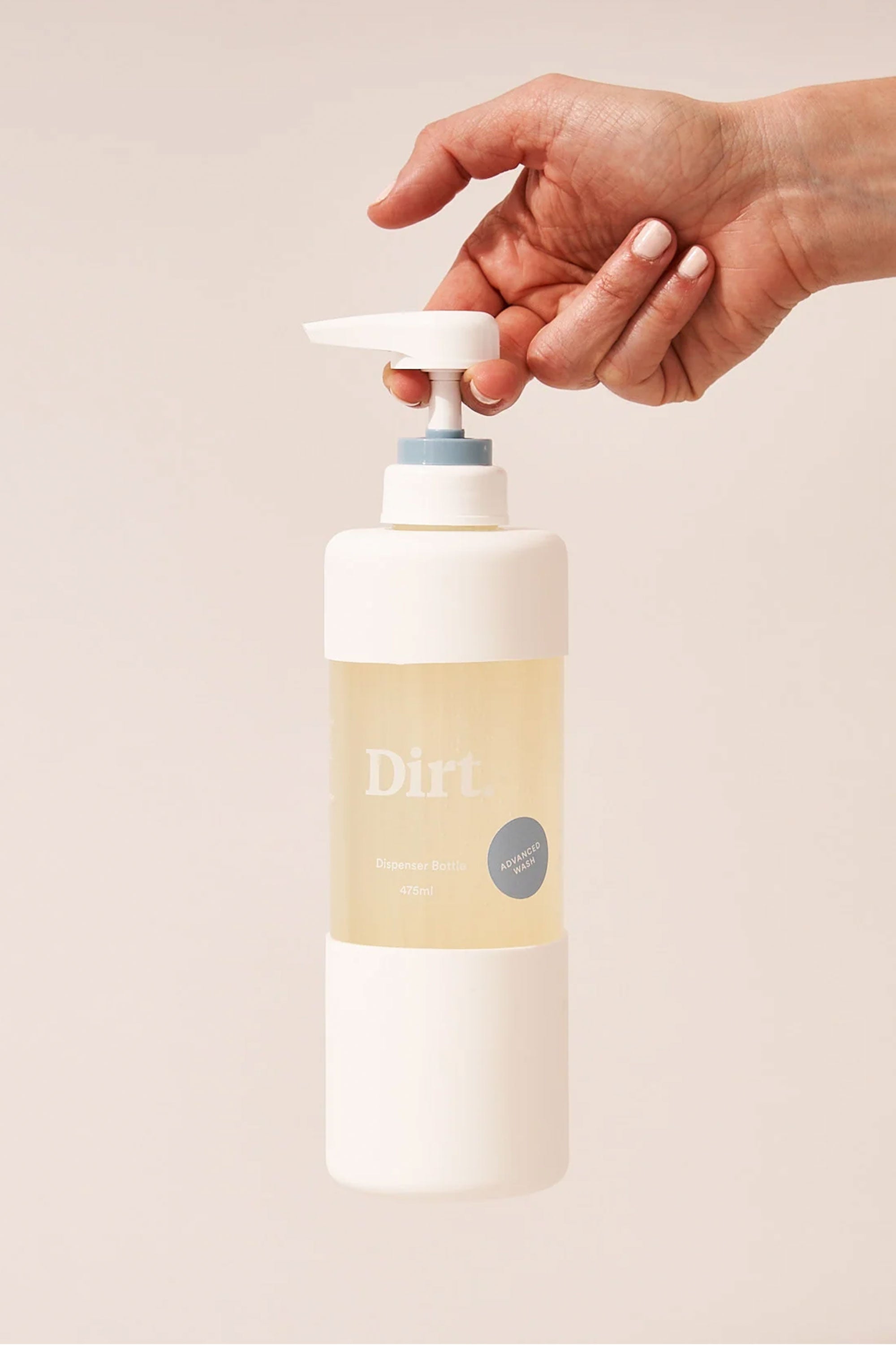 A hand presses the pump of a white and clear bottle labeled "Other Advanced Wash Starter Pack," dispensing liquid soap for odour removal, against a plain light background.