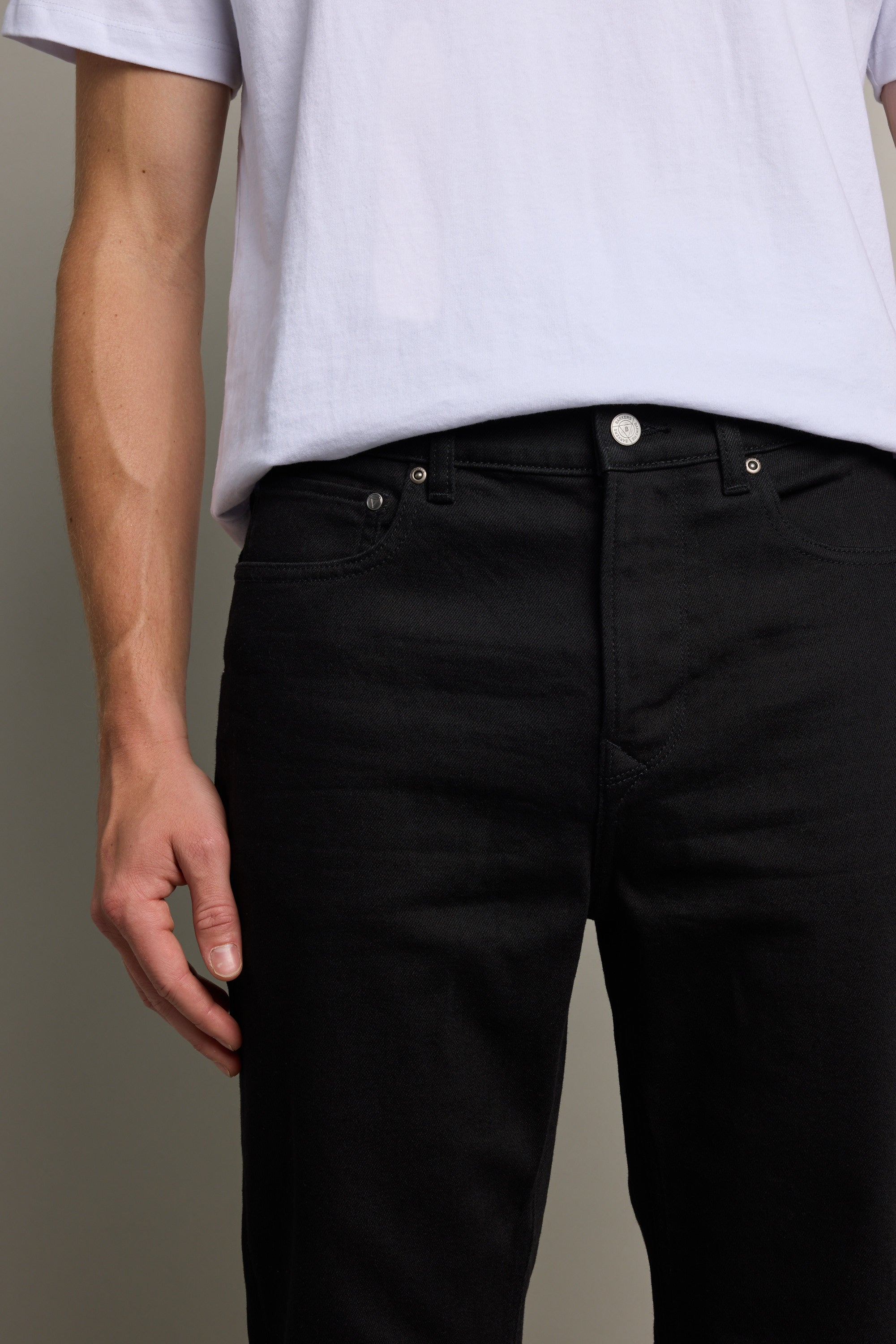 A person is shown from waist to mid-thigh wearing a white t-shirt and Barkers Rambler Denim Slim Jean, with one arm relaxed at their side against a neutral background.
