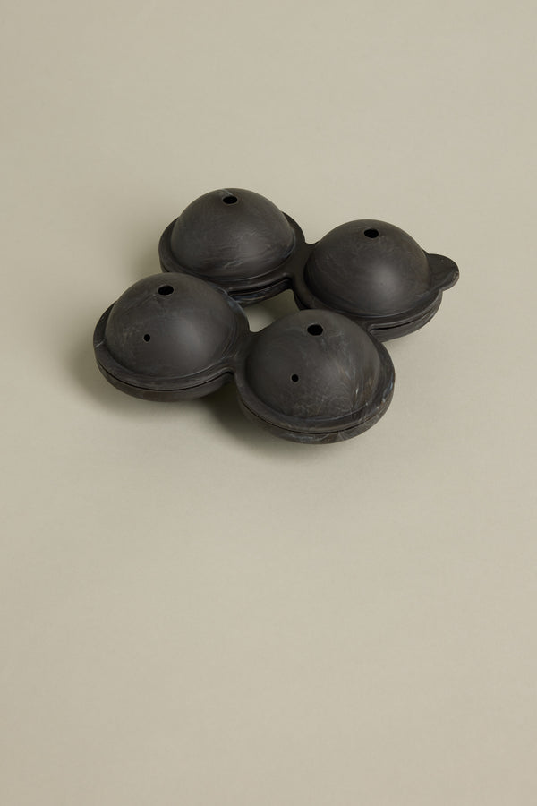 The Barkers Ice Tray Sphere Marble Black features four compartments and small top holes, ideal for crafting large round ice spheres—perfect for cocktails. Displayed here on a plain light beige surface.