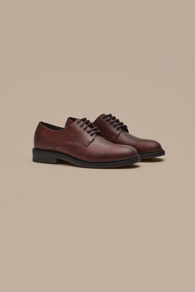 The Barkers Saville Derby Shoe features classic brown leather with black soles and laces, showcased on a beige background—a prime example of quality Portuguese craftsmanship.