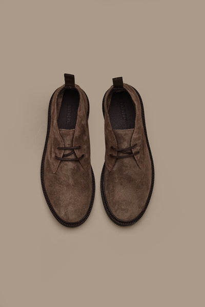 The Barkers Howarth Desert Boot features brown suede, rounded toes, dark soles, and back pull tabs. Displayed side by side from above on a light brown background, these essential boots combine quality and style.