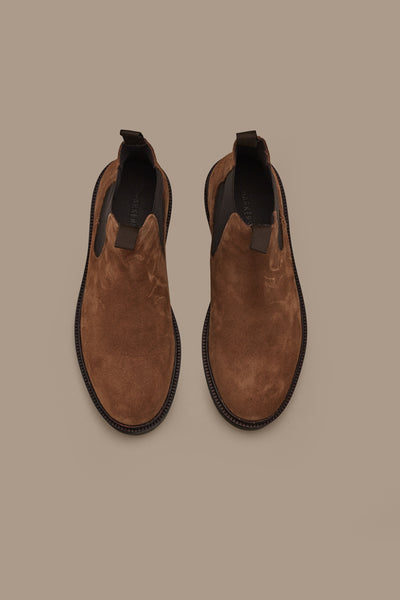The Barkers Johnson Chelsea Boot features brown suede leather and black soles, shown from above on a matching brown background—an ideal men's footwear choice.