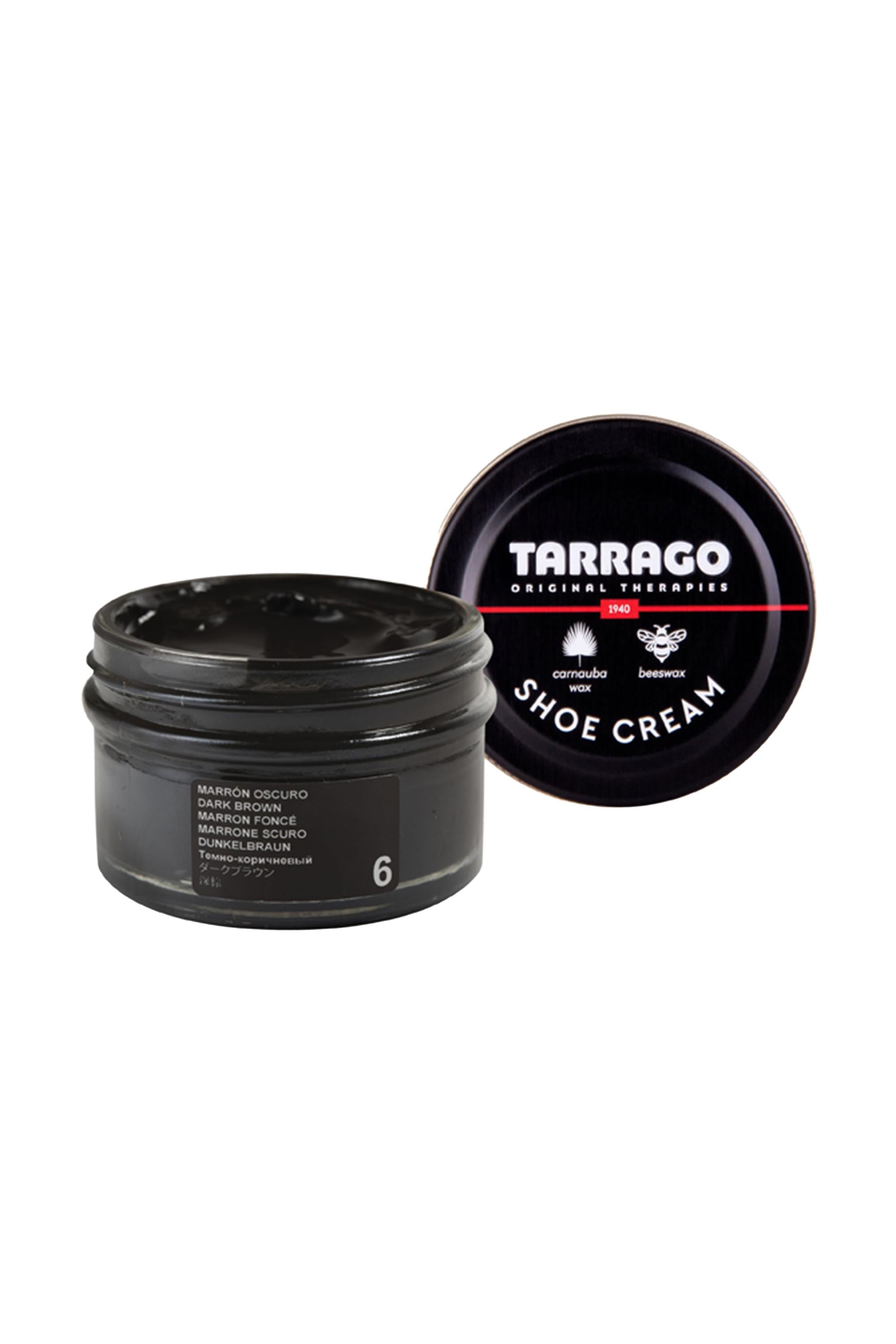 A round black Tarrago Shoe Cream jar with its lid off reveals the dark cream inside. The lid, displaying "Tarrago" and product details in white, highlights that it nourishes leather with carnauba wax.
