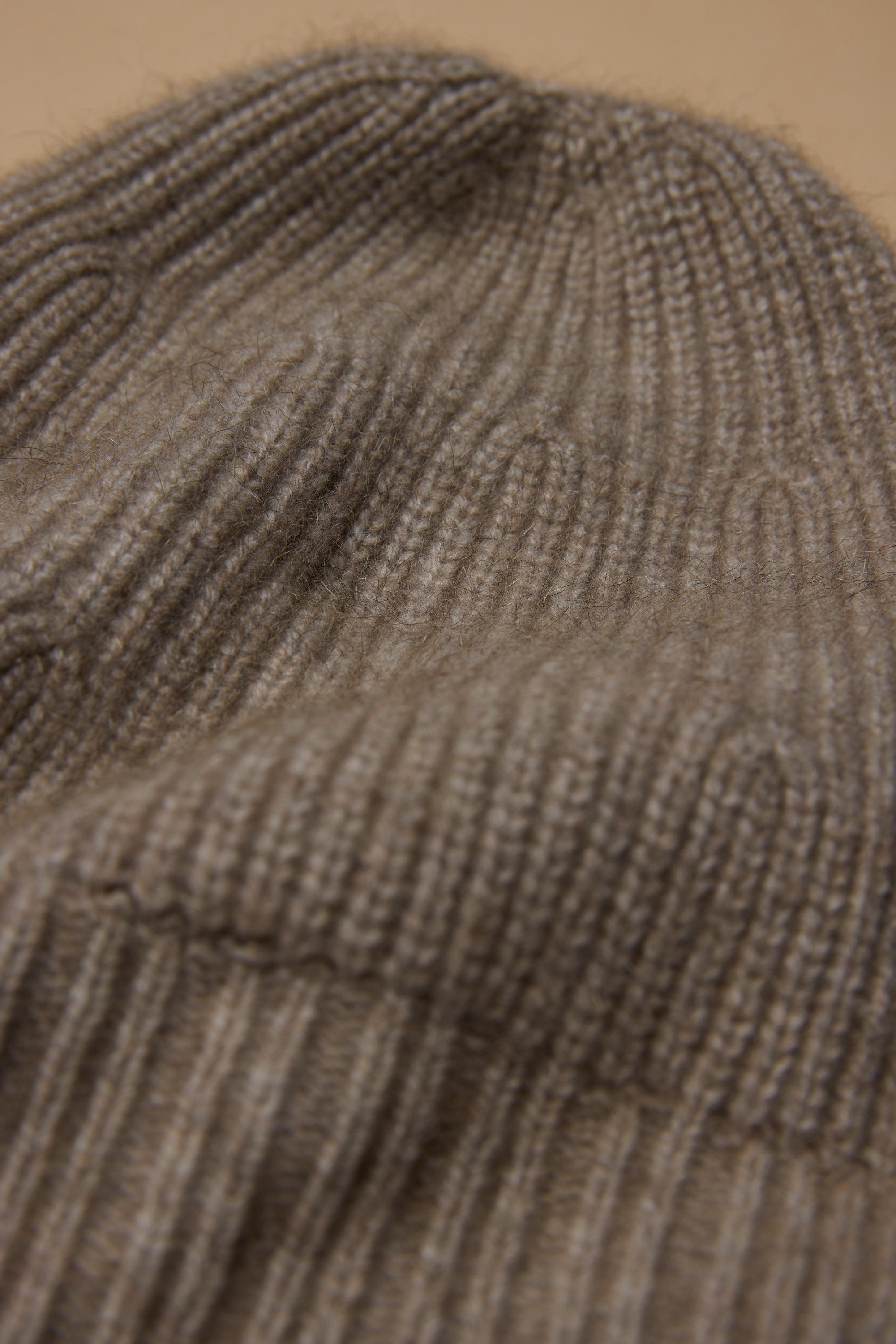 Close-up of ribbed brown knit fabric from the Woolyarns Perino NZ Made Perino Beanie, showing detailed texture and stitches.