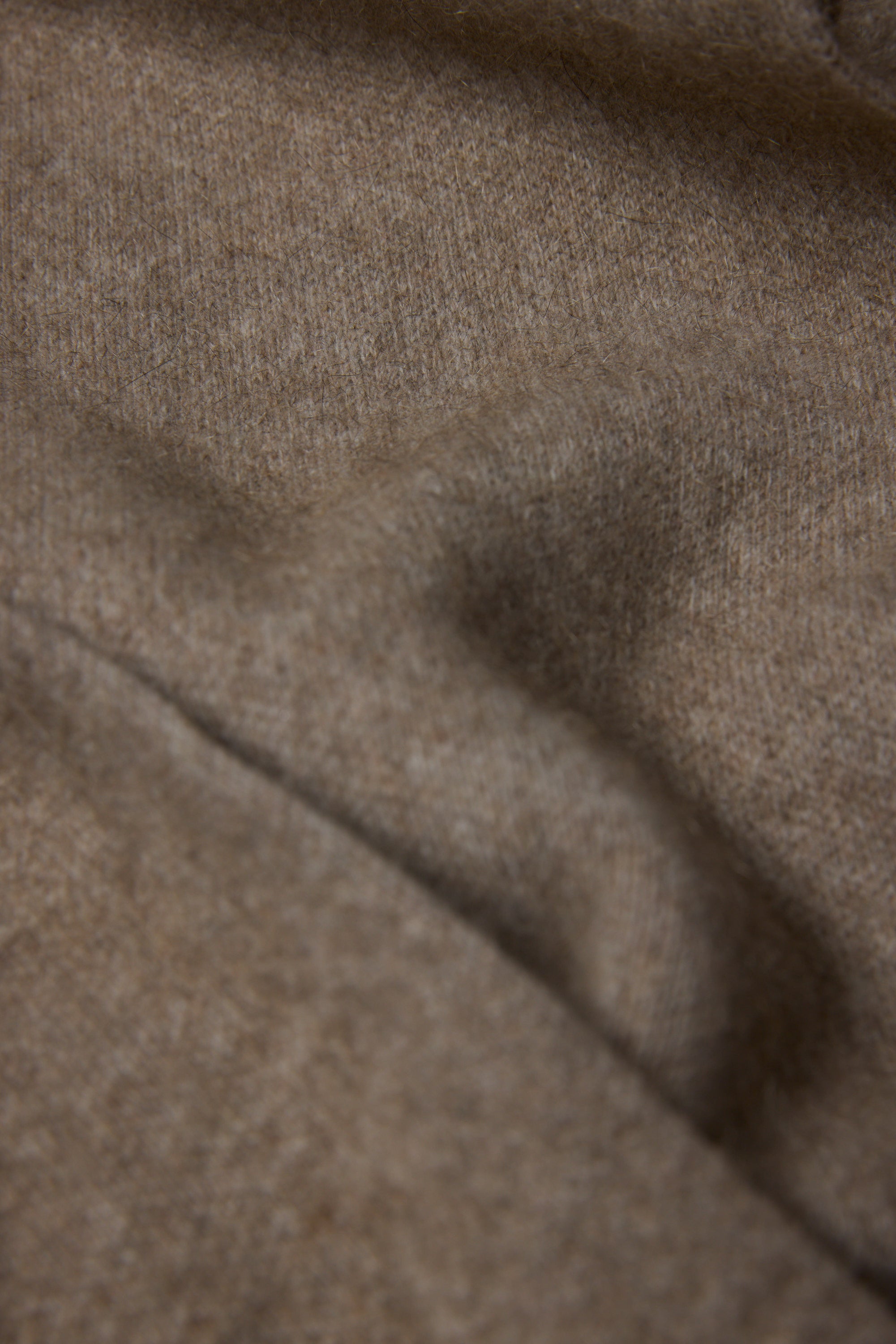 Close-up of the NZ Made Perino Scarf by Woolyarns Perino, showing soft, light brown merino possum silk fabric with a fuzzy texture and gentle folds. Crafted in New Zealand for premium accessories.