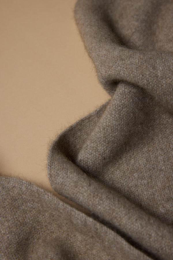 A close-up of soft, light brown merino possum silk blend wool, slightly fuzzy and casually draped on beige—highlighting the NZ Made Perino Scarf by Woolyarns Perino.