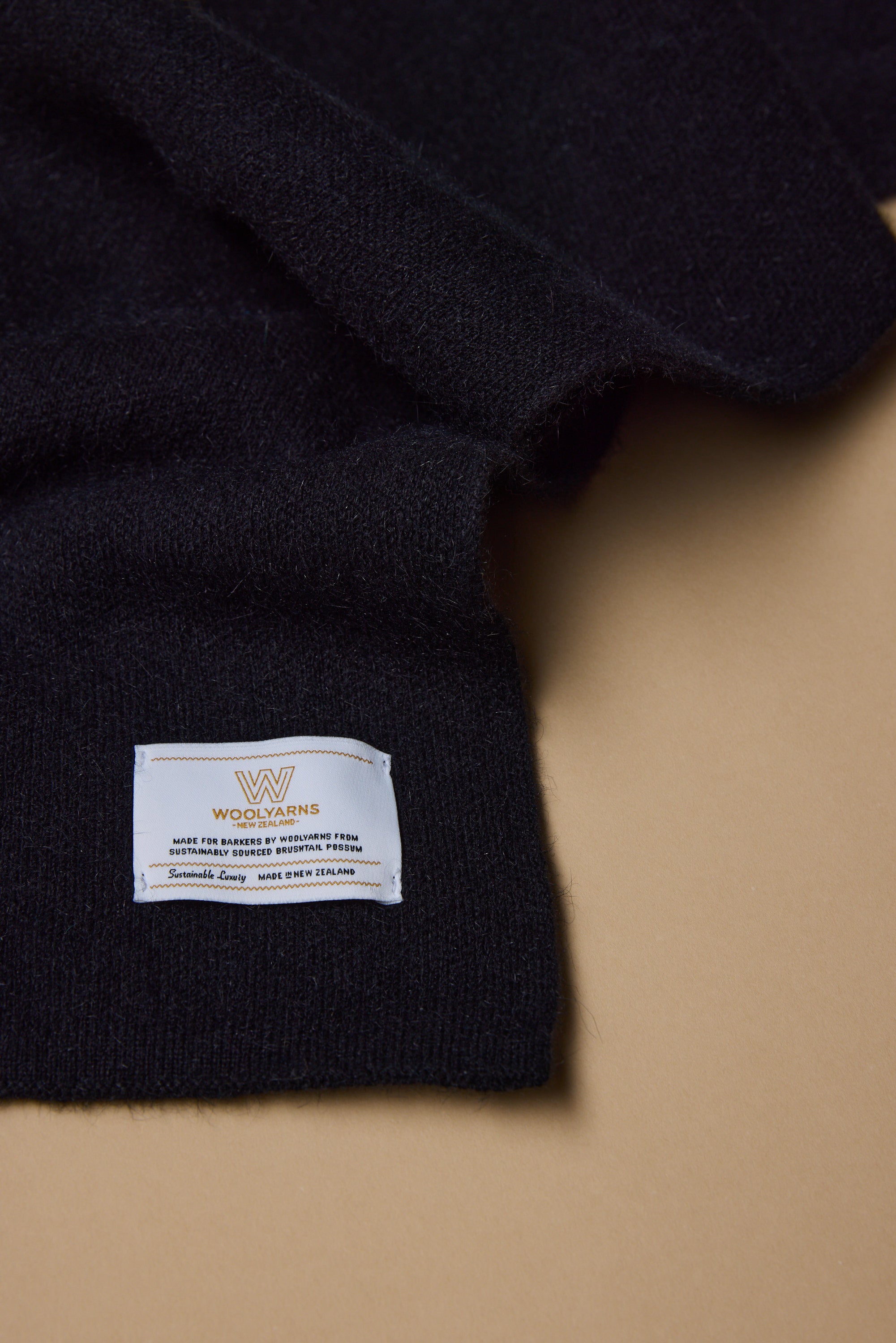 A close-up of the NZ Made Perino Scarf by Woolyarns Perino, shown on a beige surface with a white label highlighting its pure new wool and New Zealand origin—ideal for those who value quality accessories.