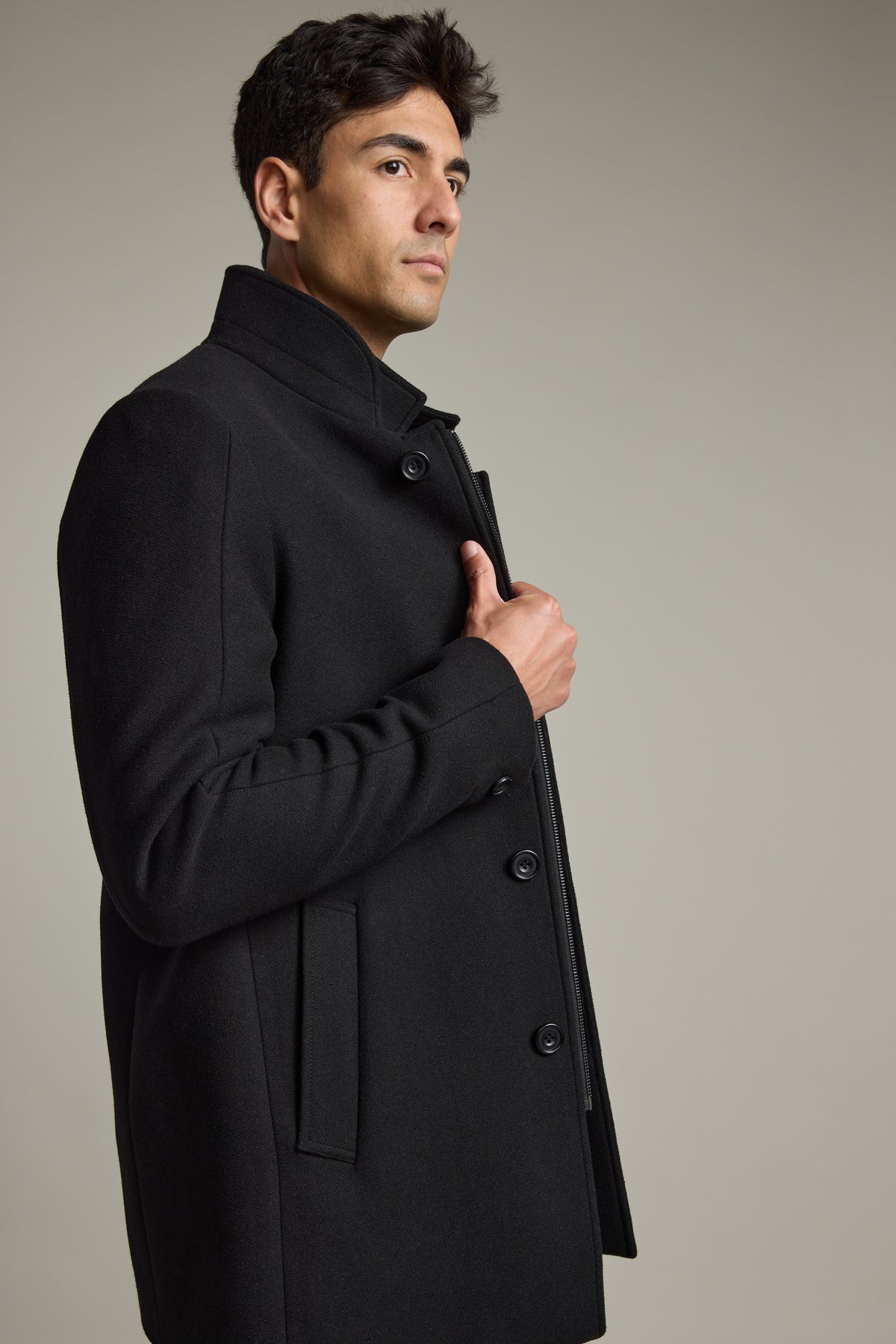 Man in a black Barkers Raymond Coat looks sideways against a plain, light background.
