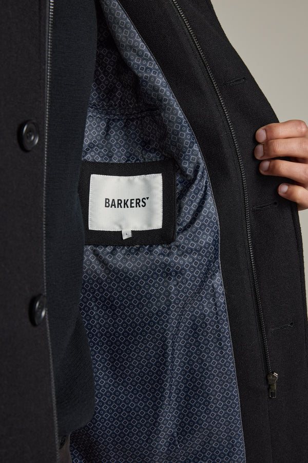 A hand parts a Raymond Coat to reveal its patterned lining and Barkers brand label inside.