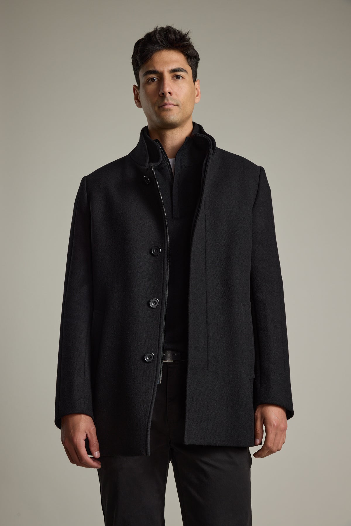 Man in a Barkers Raymond Coat and dark pants stands against a plain neutral background.