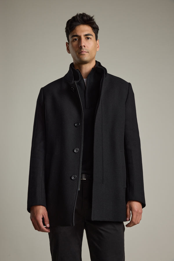 Man in a Barkers Raymond Coat and dark pants stands against a plain neutral background.