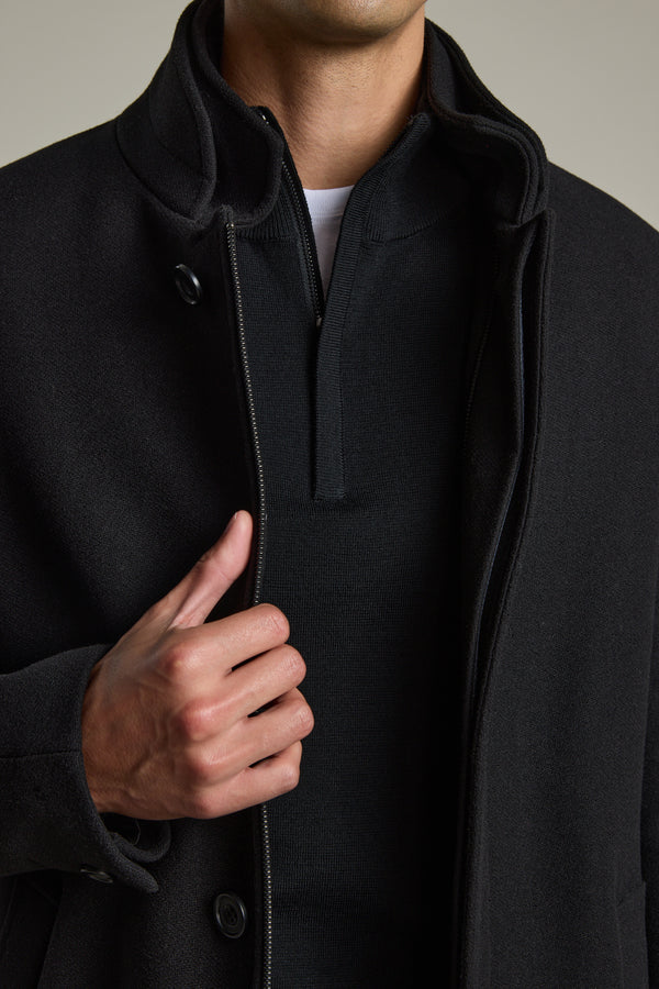 Man in Barkers Raymond Coat, black wool blend, holding the overcoat open with left hand.