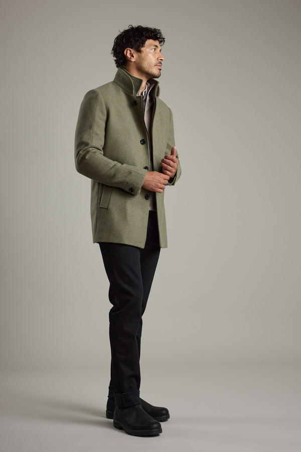 Man in a Barkers Raymond Coat, black pants, and boots stands against a plain background.