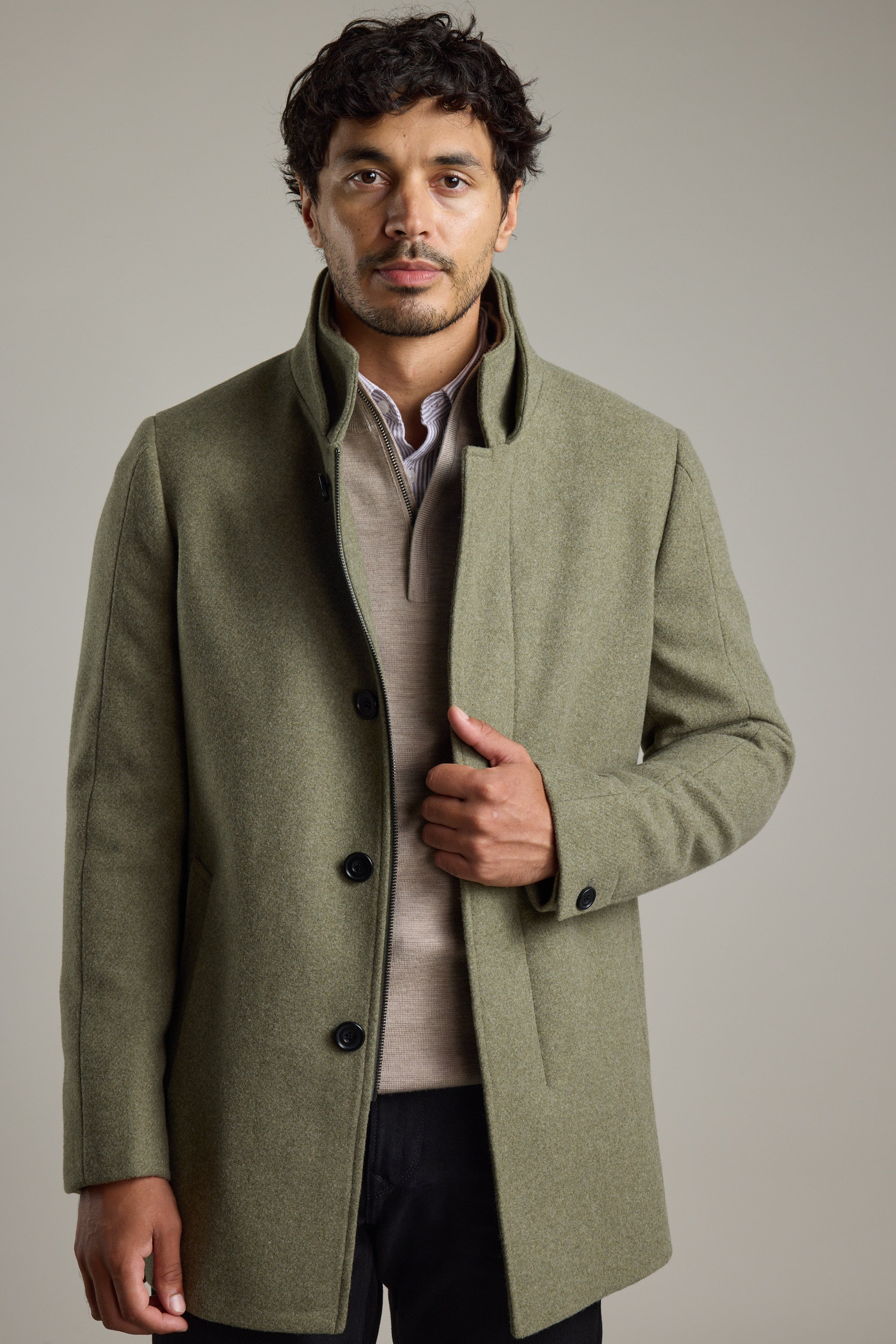 Man wears Barkers Raymond Coat over a beige sweater against a plain background.