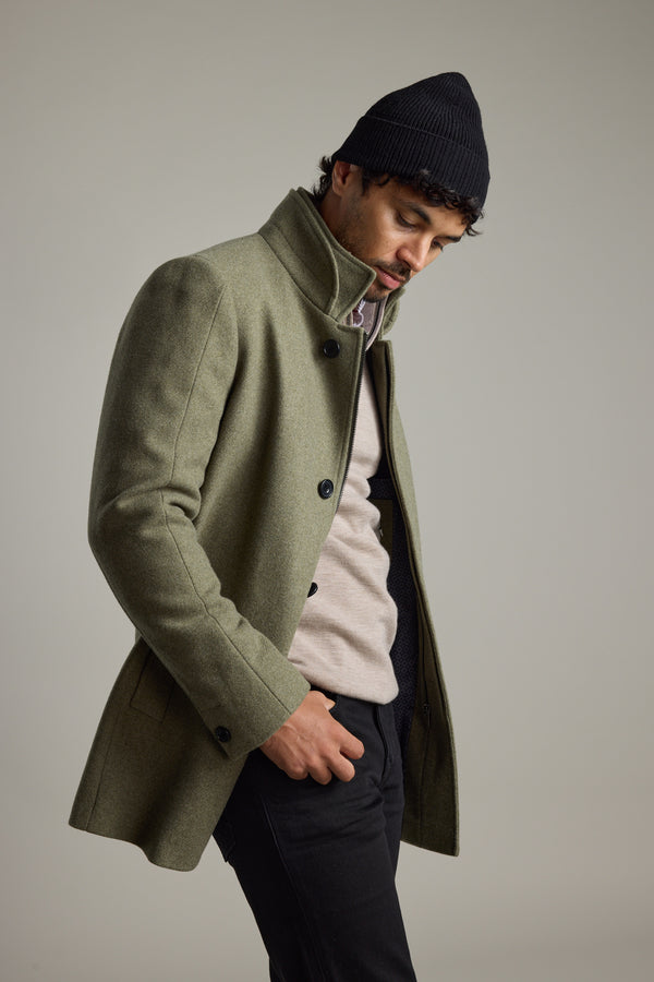 Man wearing Barkers Raymond Coat in green wool blend and black beanie, looking down.