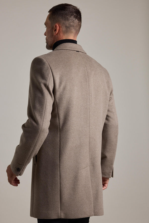 A man with short hair is seen from behind wearing a light brown Barkers Morrison Coat, a tailored wool blend, over a black shirt against a plain light background.