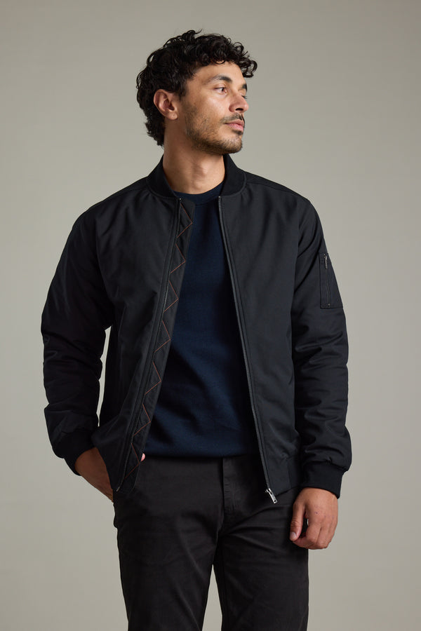 Man in Barkers Dunhill Bomber Jacket and dark pants, standing with one hand in pocket.