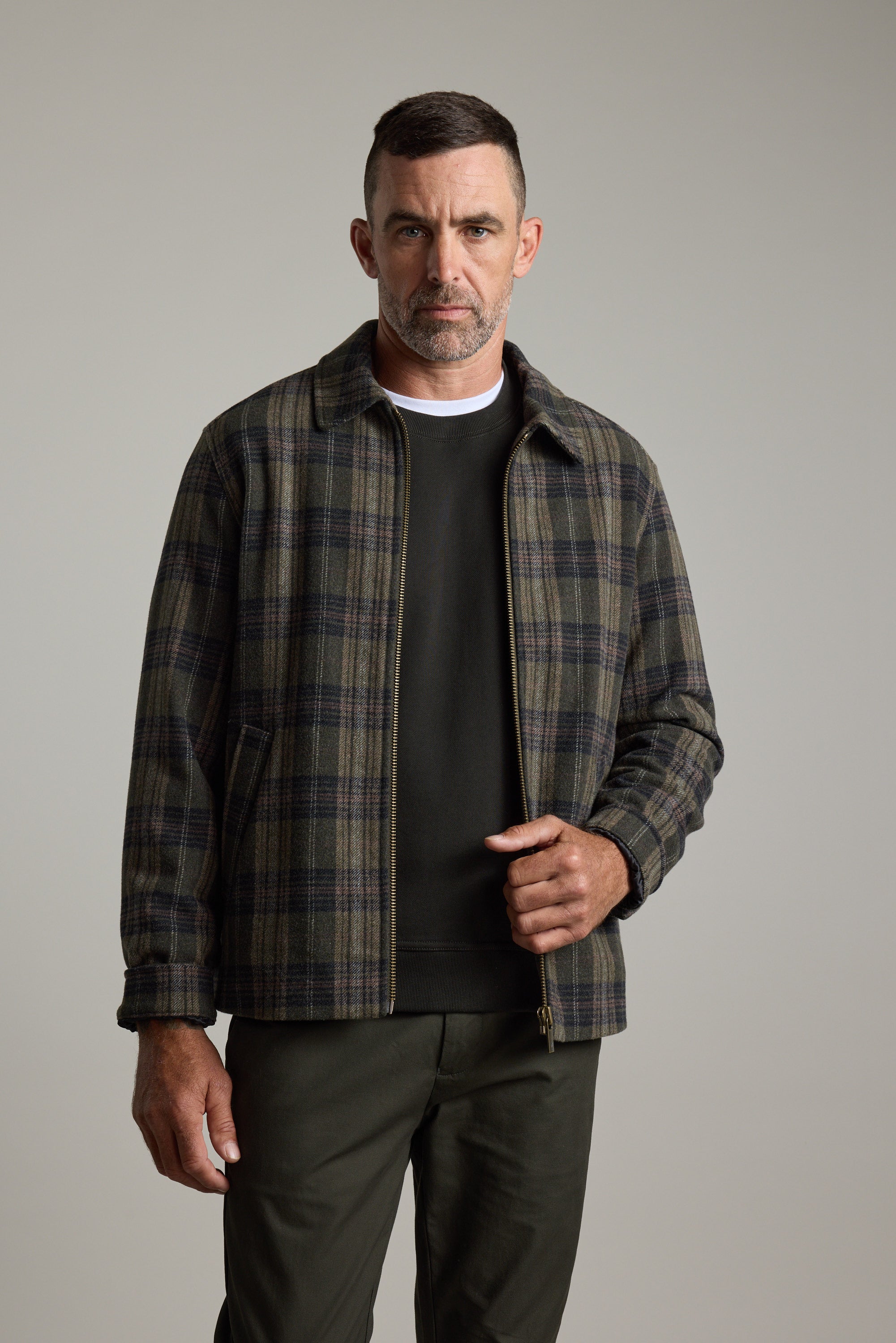 Man wears Barkers Zermatt Wool Jacket, standing against a plain, light gray background.