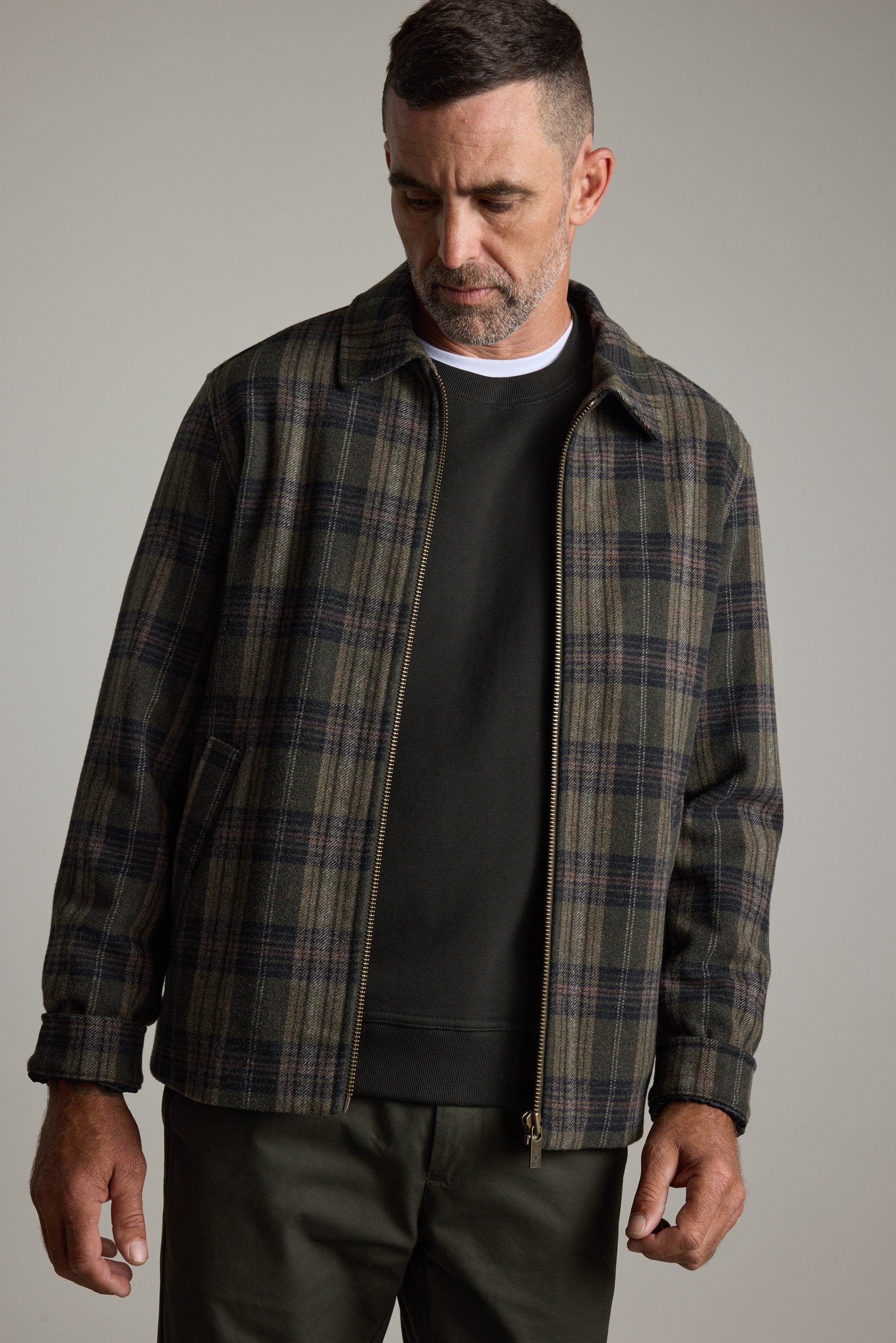 Man in Barkers Zermatt Wool Jacket over black shirt, looking down with a neutral expression.