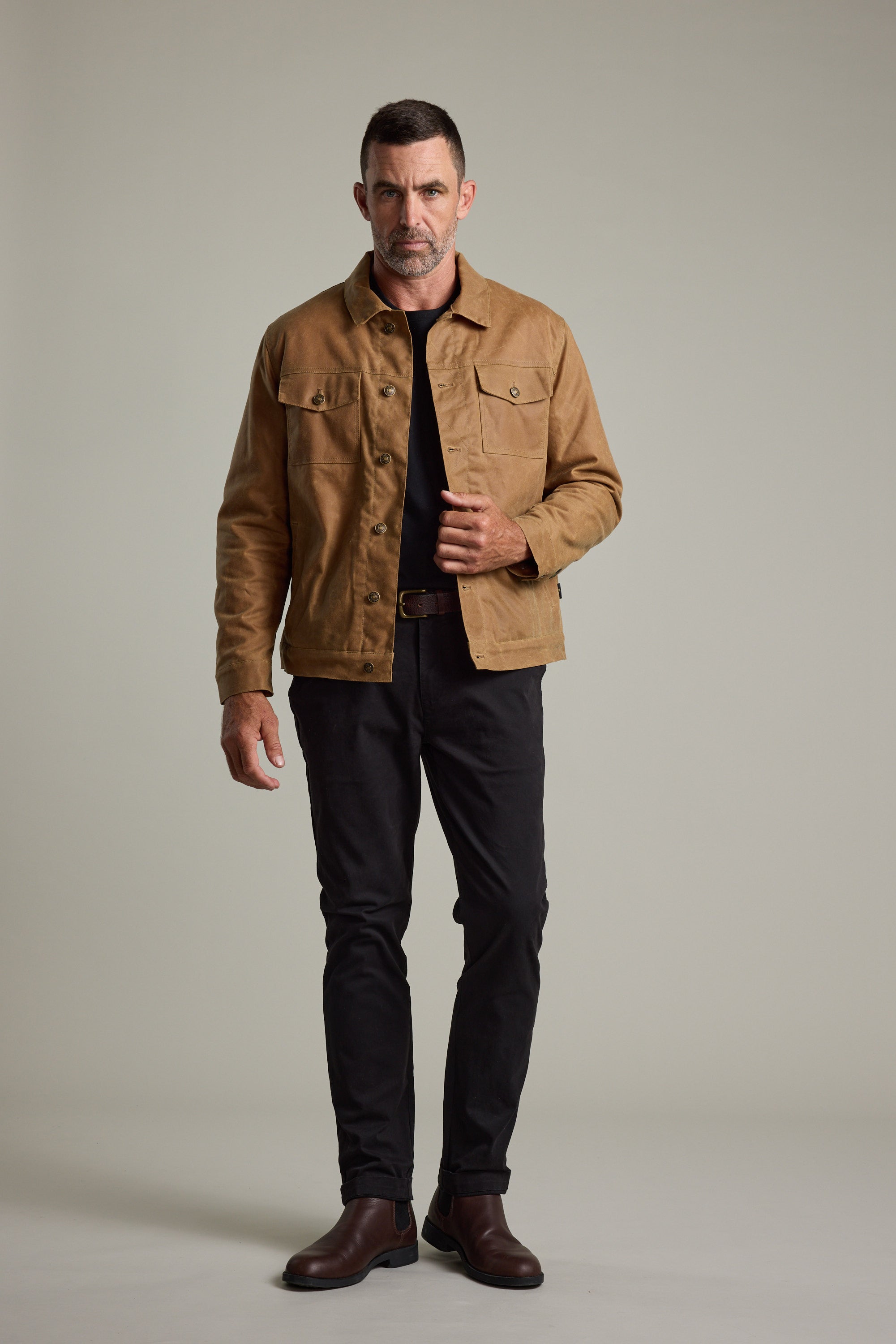 Man wearing the Barkers Benson Waxed Cotton Sherpa Jacket, black shirt, pants, and brown boots.