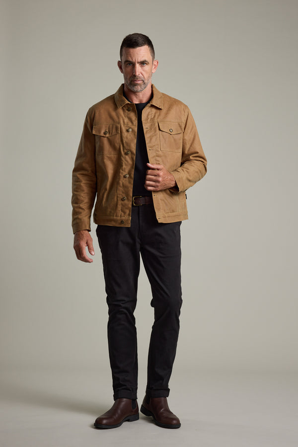 Man wearing the Barkers Benson Waxed Cotton Sherpa Jacket, black shirt, pants, and brown boots.