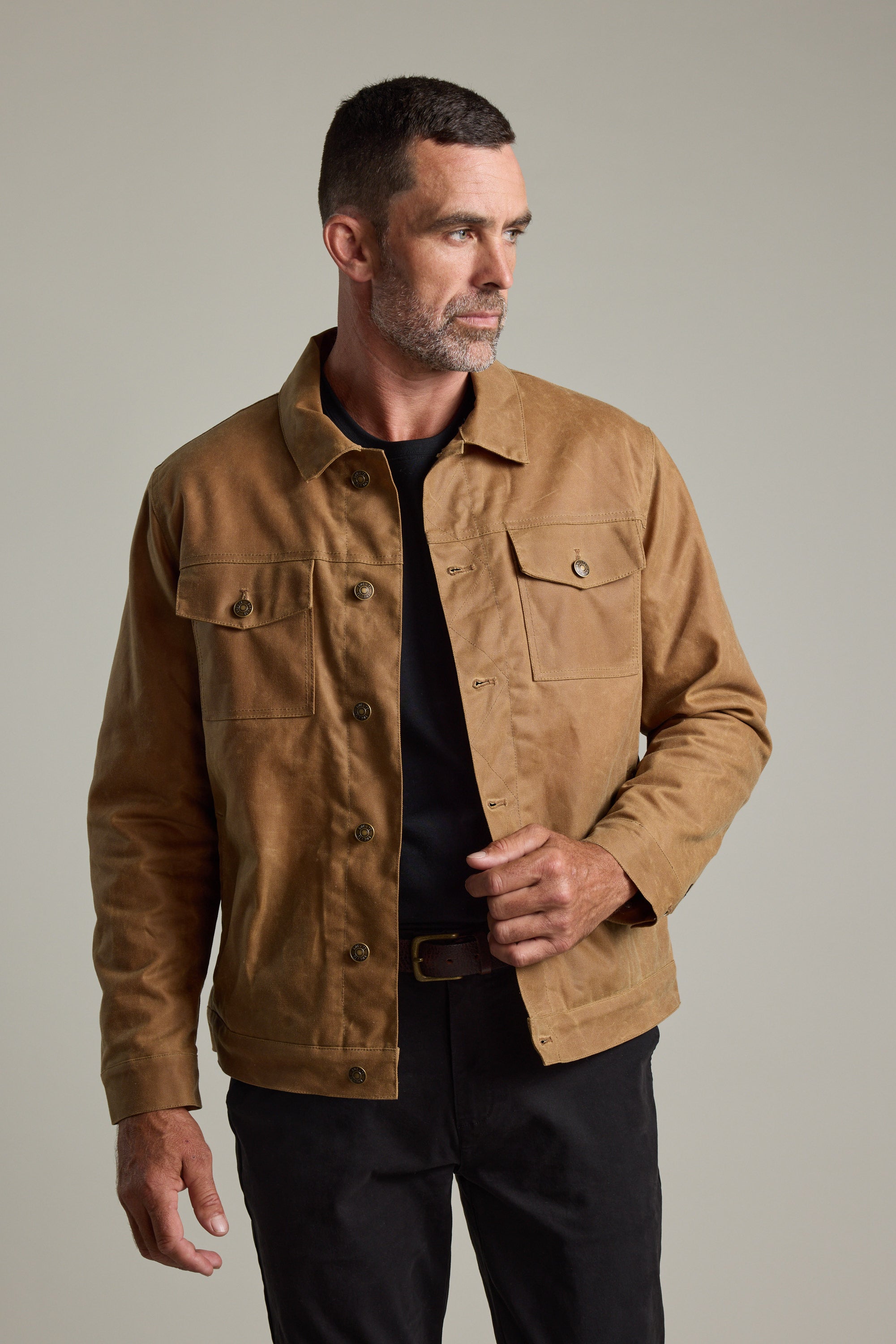 Man wears Barkers Benson Waxed Cotton Sherpa Jacket over black shirt against plain background.