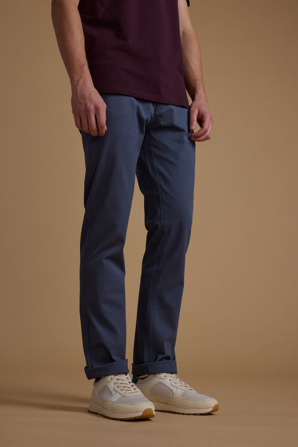 A person, shown from shoulders down against a beige background, wears a burgundy shirt, white sneakers, and Barkers Beckett 5-Pocket Pant featuring classic five-pocket styling.