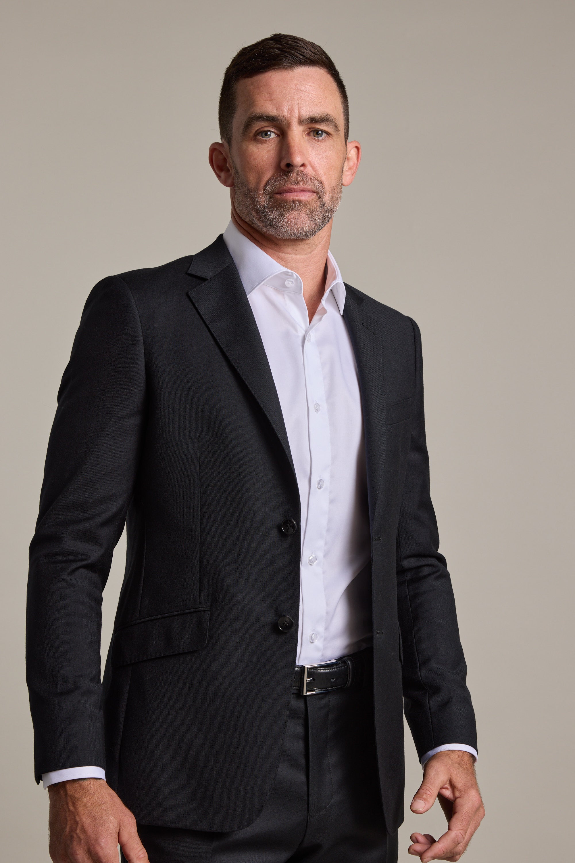 A man with short dark hair and a trimmed beard wears the Barkers Mayfair ZQrx Suit Jacket, crafted from fine merino wool, over a white dress shirt. He stands against a plain light background, looking confidently at the camera.