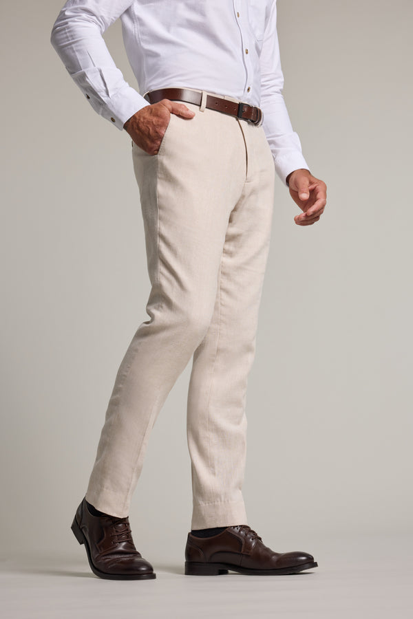 A man wears Barkers Thompson Textured Linen Pant in beige, white shirt, brown belt, and shoes.