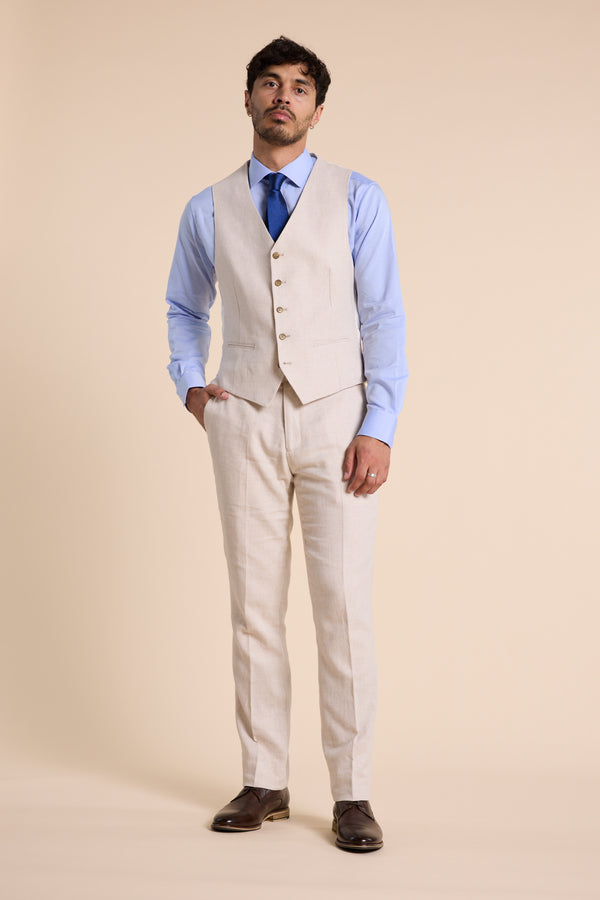 Man in Barkers Thompson Textured Linen Pant, blue shirt, and tie against a beige backdrop.