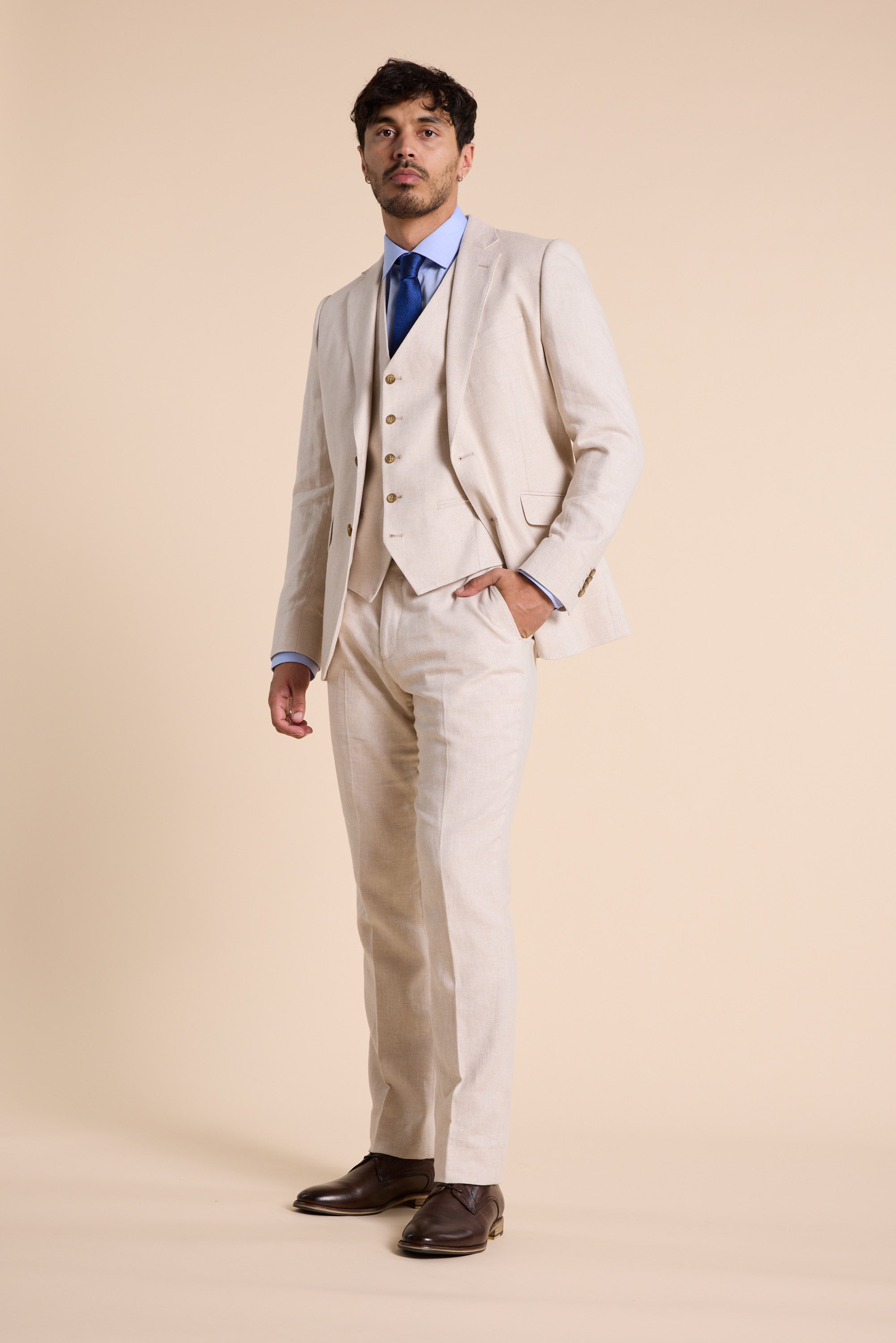 Man in Barkers Thompson Textured Linen Pant with blue shirt, tie, and beige background.