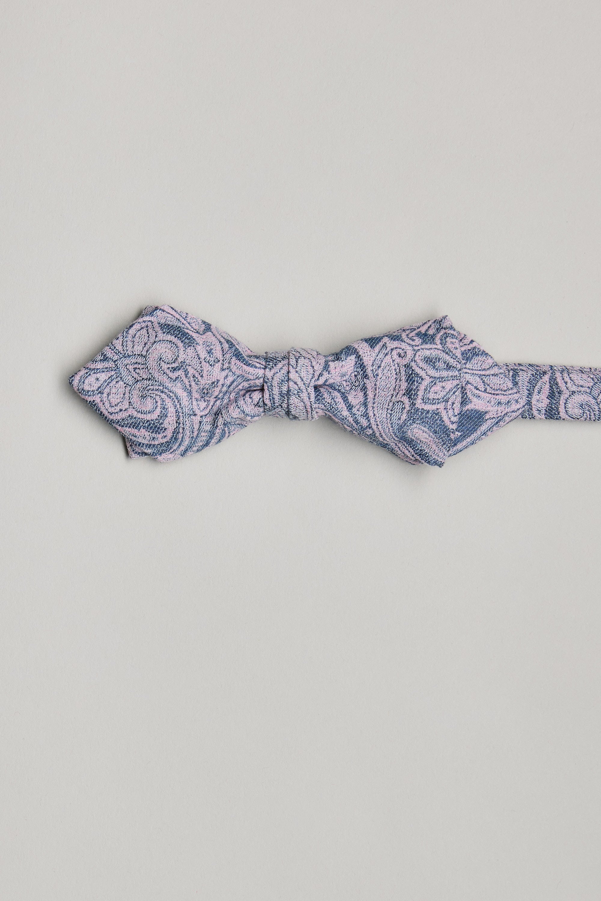 The Barkers Parisian Lincoln Bow Tie features a blue base with a light pink paisley pattern, handmade in New Zealand and shown on a plain white background.