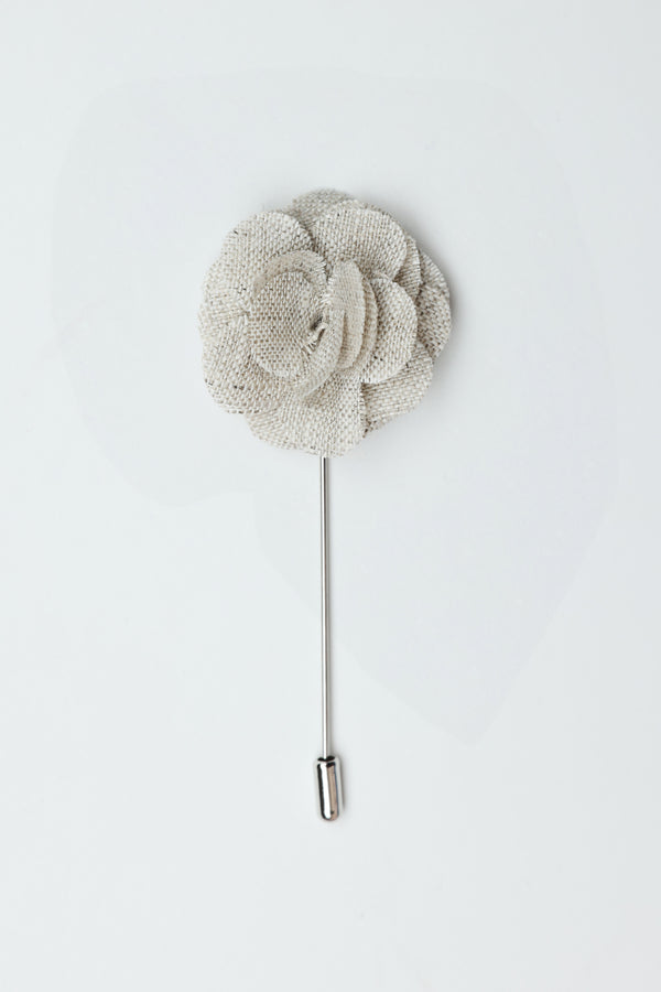 The Parisian Fraser Flower Lapel Pin features a silver textured fabric flower with a long metal stem and rounded end cap—an elegant suiting accessory for any formal occasion, shown on a plain white background.