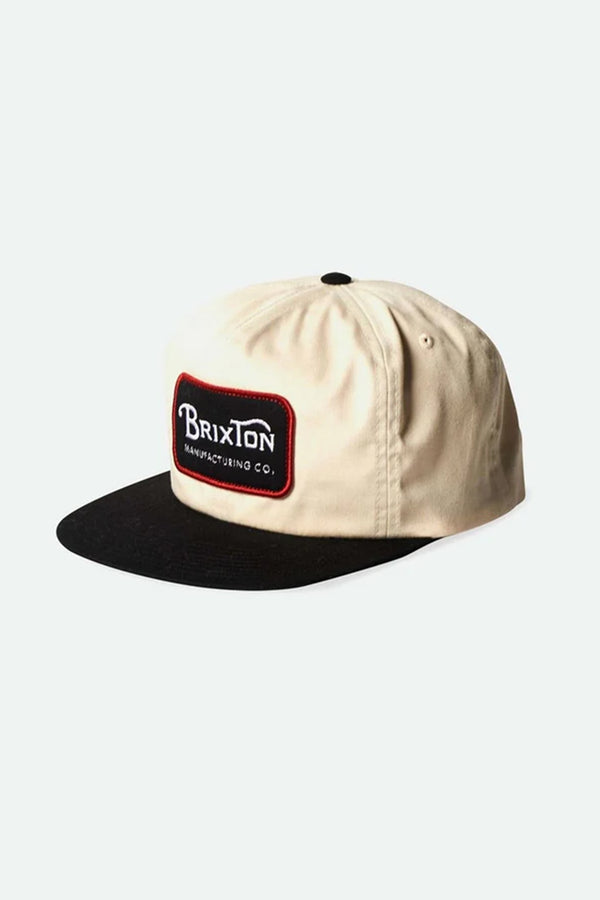The Brixton Grade HP Snap Back features a beige 6-panel design, black flat-bill, and a stitched Brixton Manufacturing Co. patch on the front panel, displayed against a plain white background.