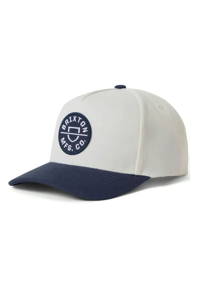 The Brixton Crest Snapback is a white cap with a dark blue brim and an embroidered Brixton Mfg. Co. patch on the front, inspired by classic style from Brixton.