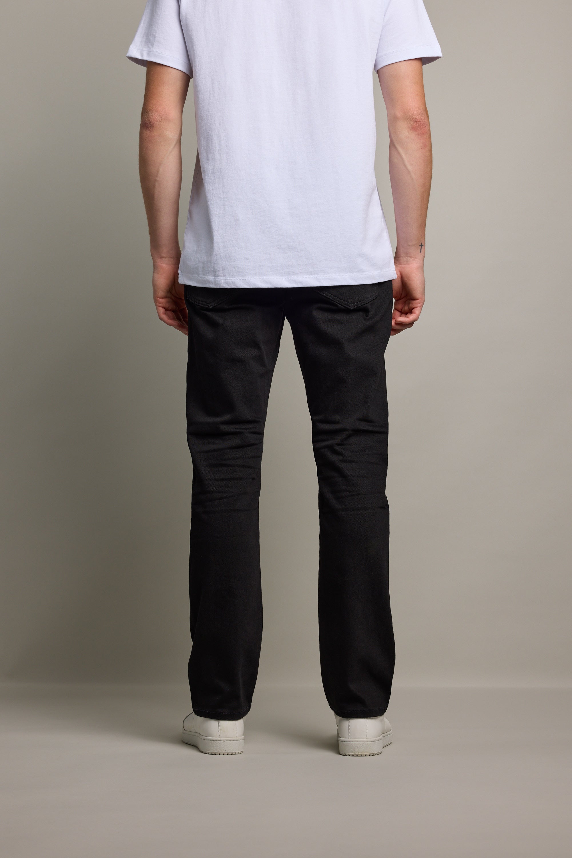 Person stands facing away in a white tee and Barkers Wanderer Denim Straight Jean.
