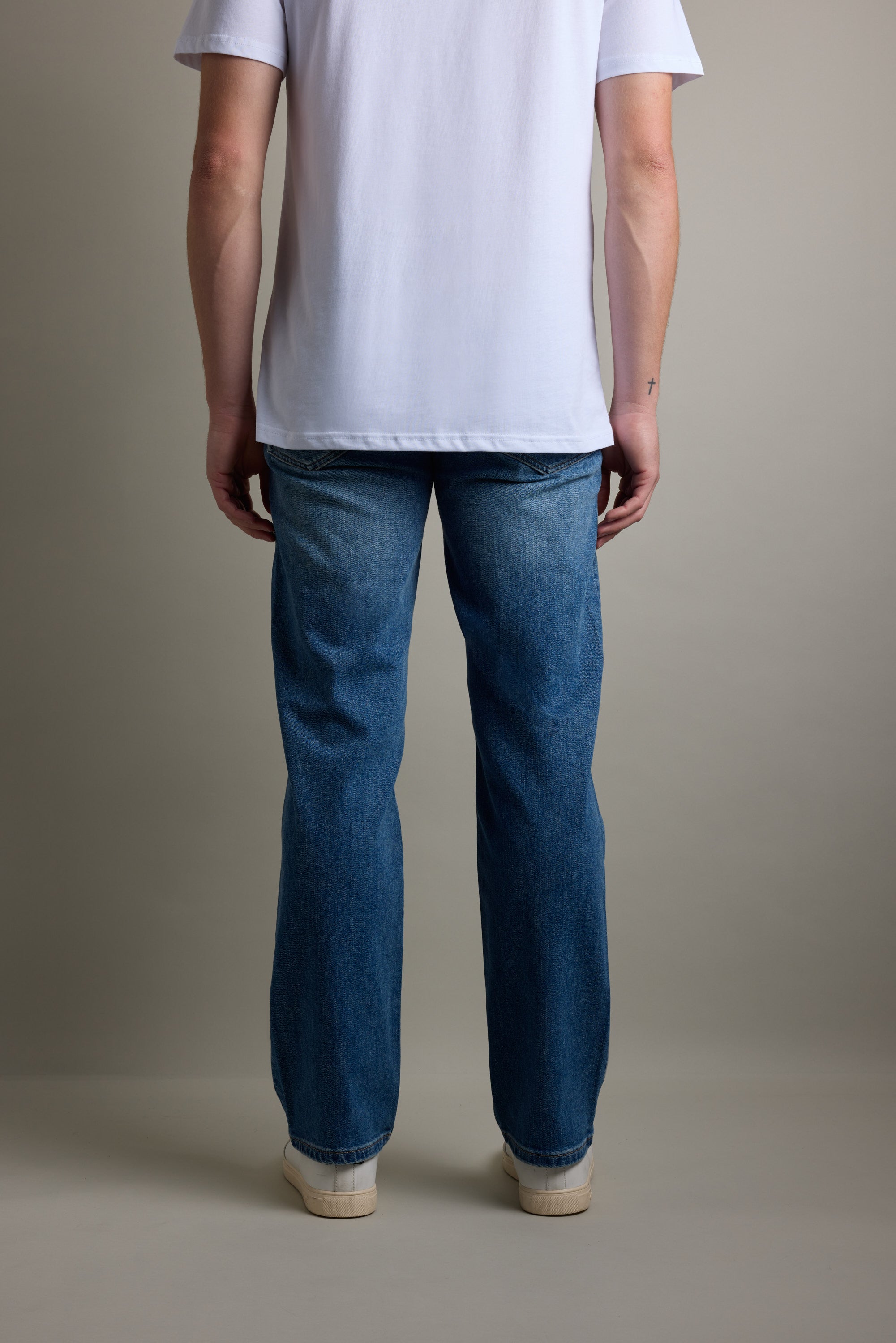 Person facing away, wearing Barkers Drifter Denim Relax Jean, white tee, and white shoes.