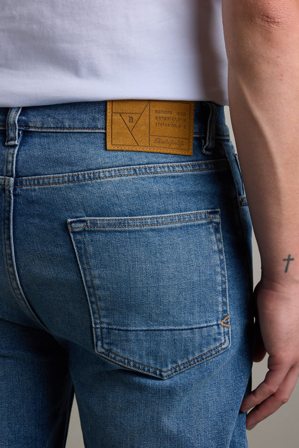 Wearing Barkers Drifter Denim Relax Jean, showing a small cross tattoo on their forearm.