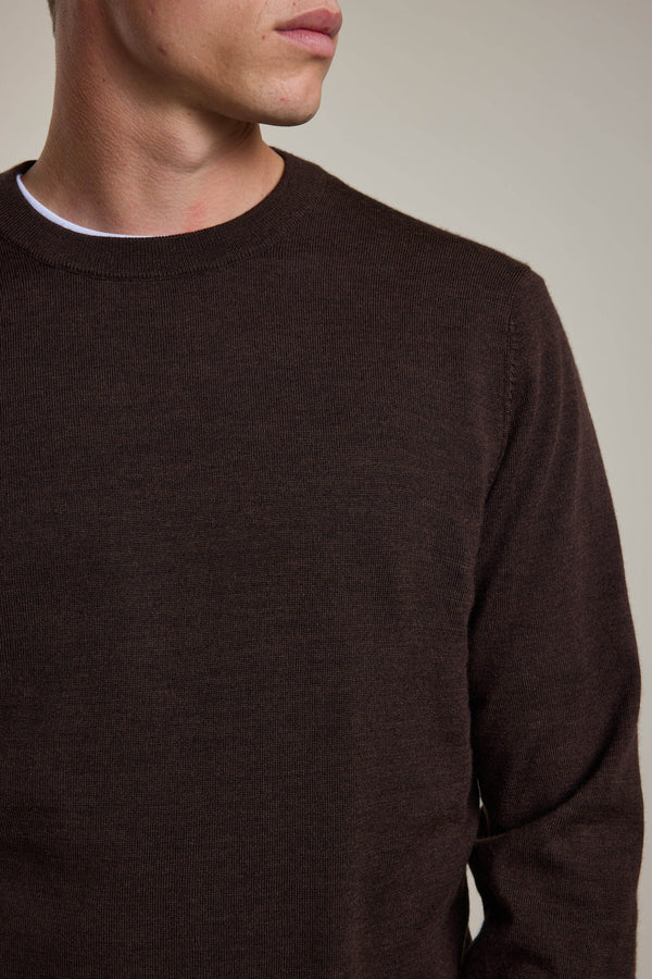 A man wears the Barkers Skyland ZQrx Merino Crew, a dark brown sustainable New Zealand merino wool sweater, over a white T-shirt. Shown from shoulders to mid-torso with his head turned slightly against a plain background.