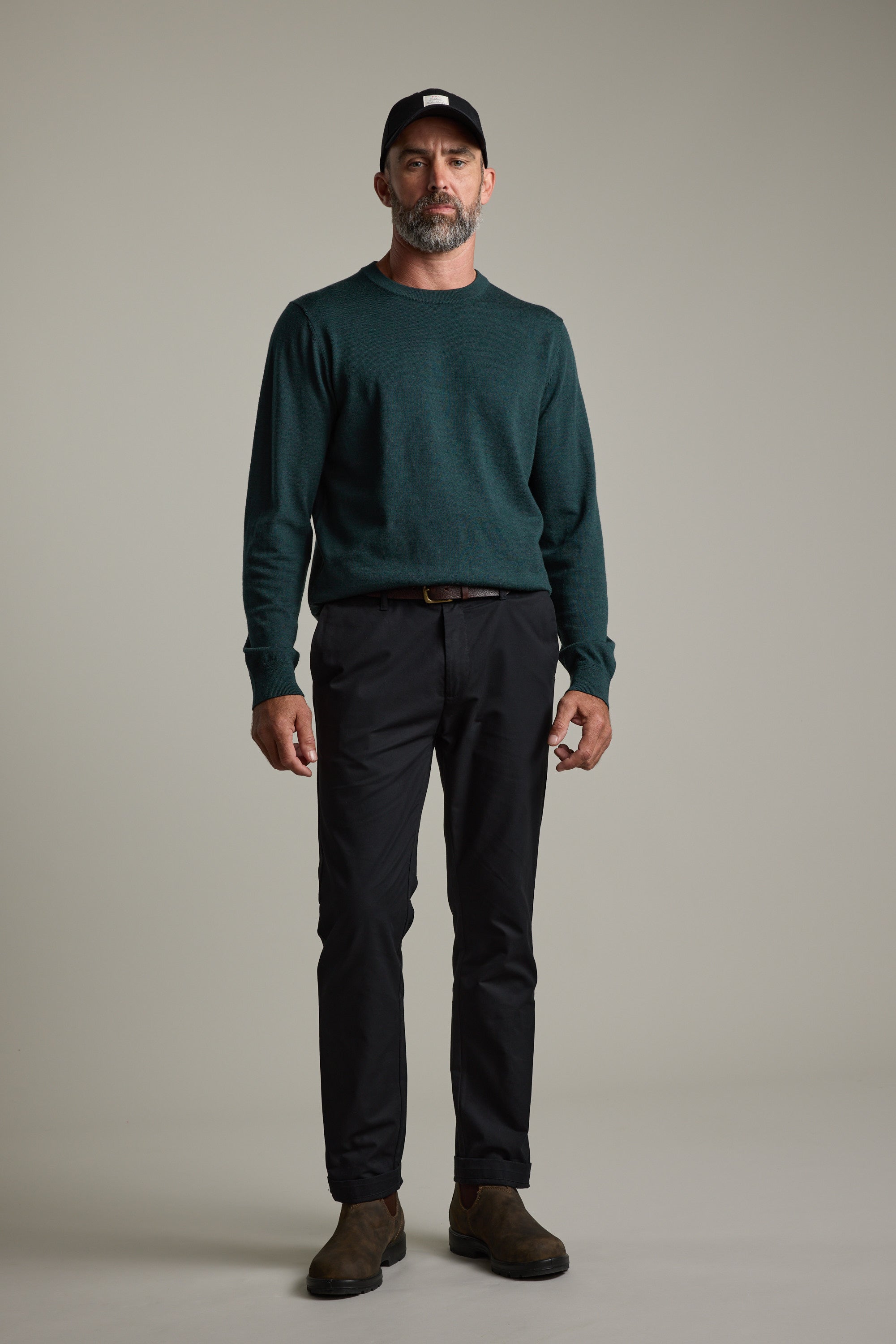 Man in Barkers Skyland ZQrx Merino Crew, black pants, and cap against a plain background.