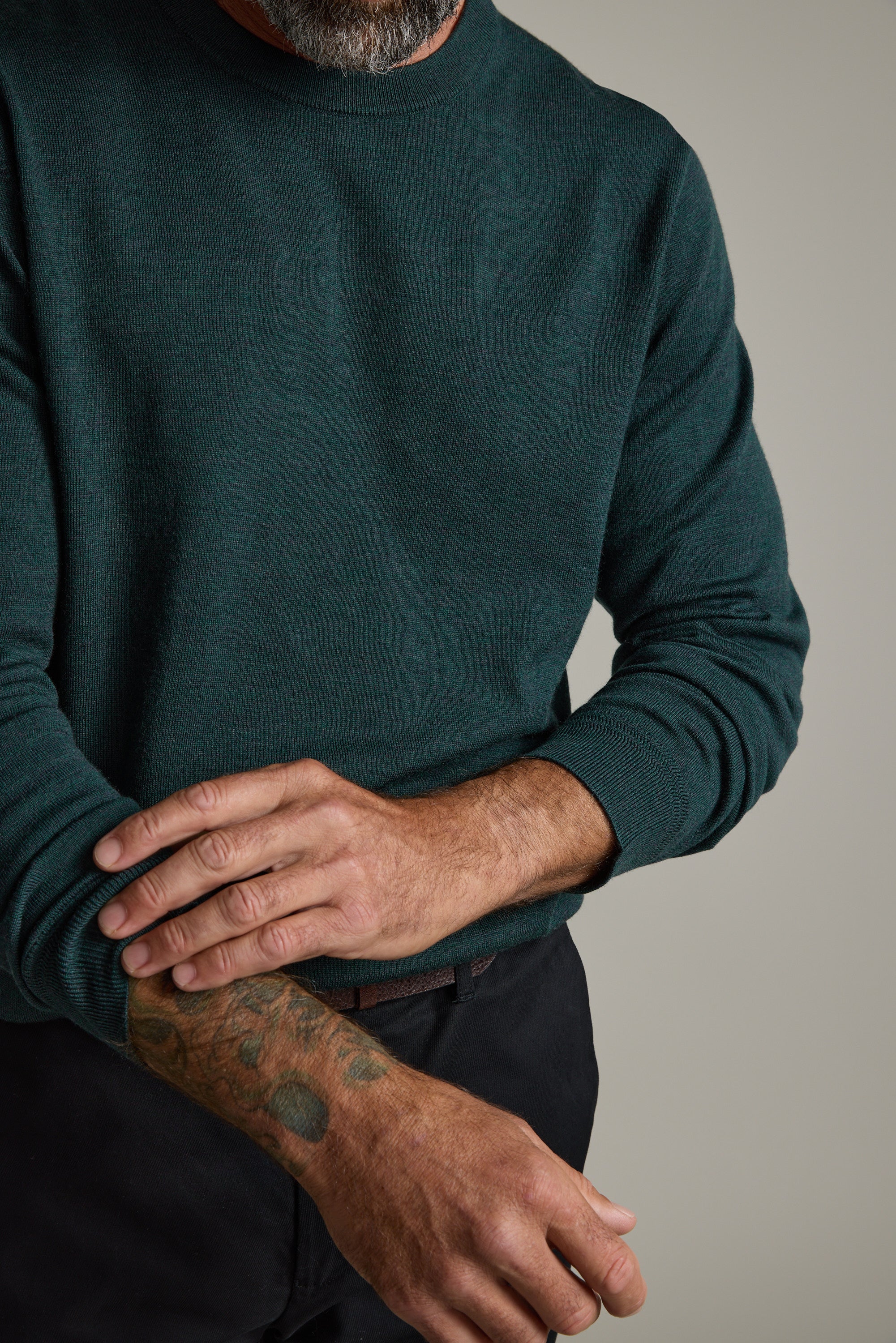 Man in a Barkers Skyland ZQrx Merino Crew rolling up his sleeve, showing a tattoo.