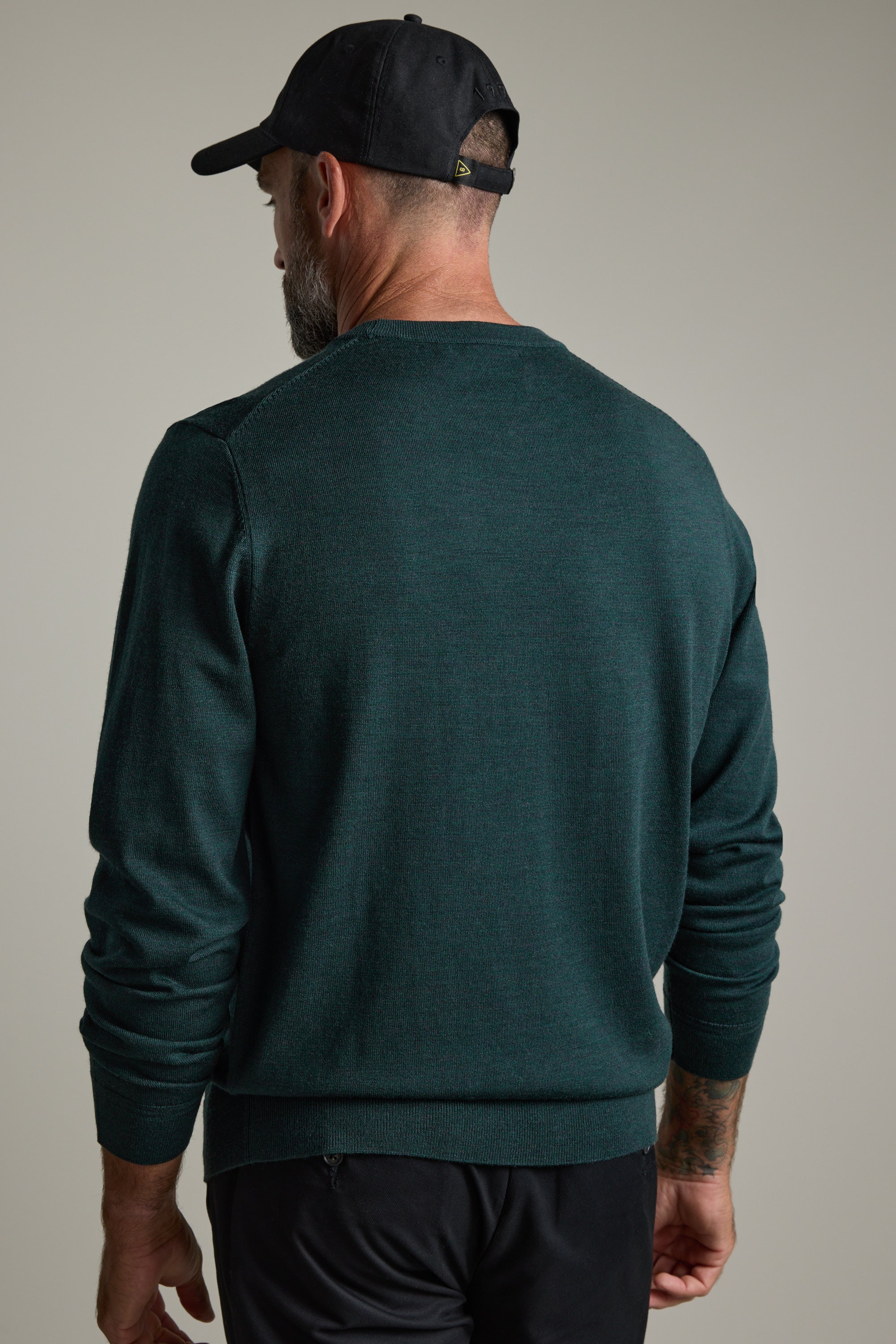 Man in a green Barkers Skyland ZQrx Merino Crew sweater and black cap, seen from behind.