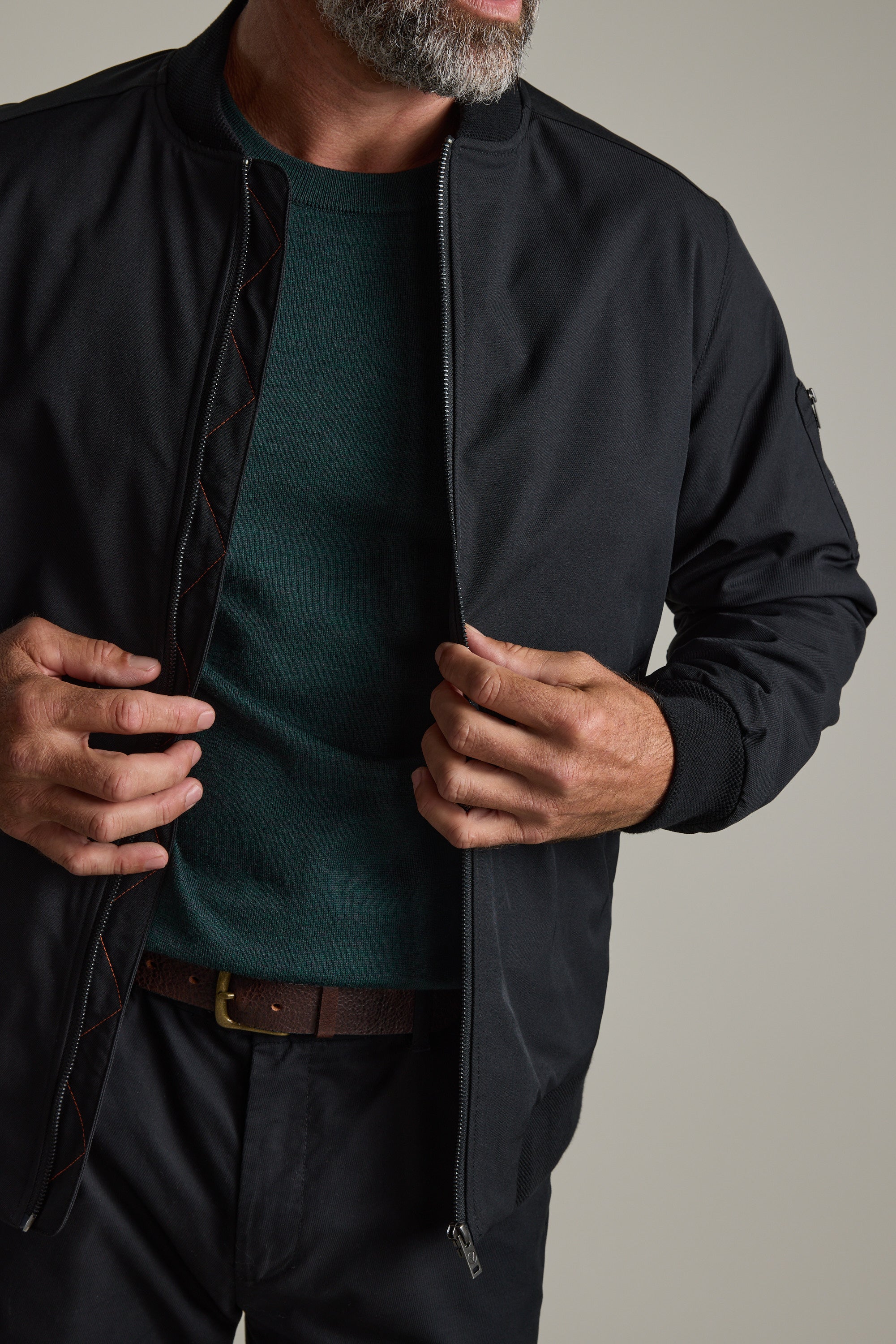 Man zipping up a black jacket over a green Barkers Skyland ZQrx Merino Crew shirt.
