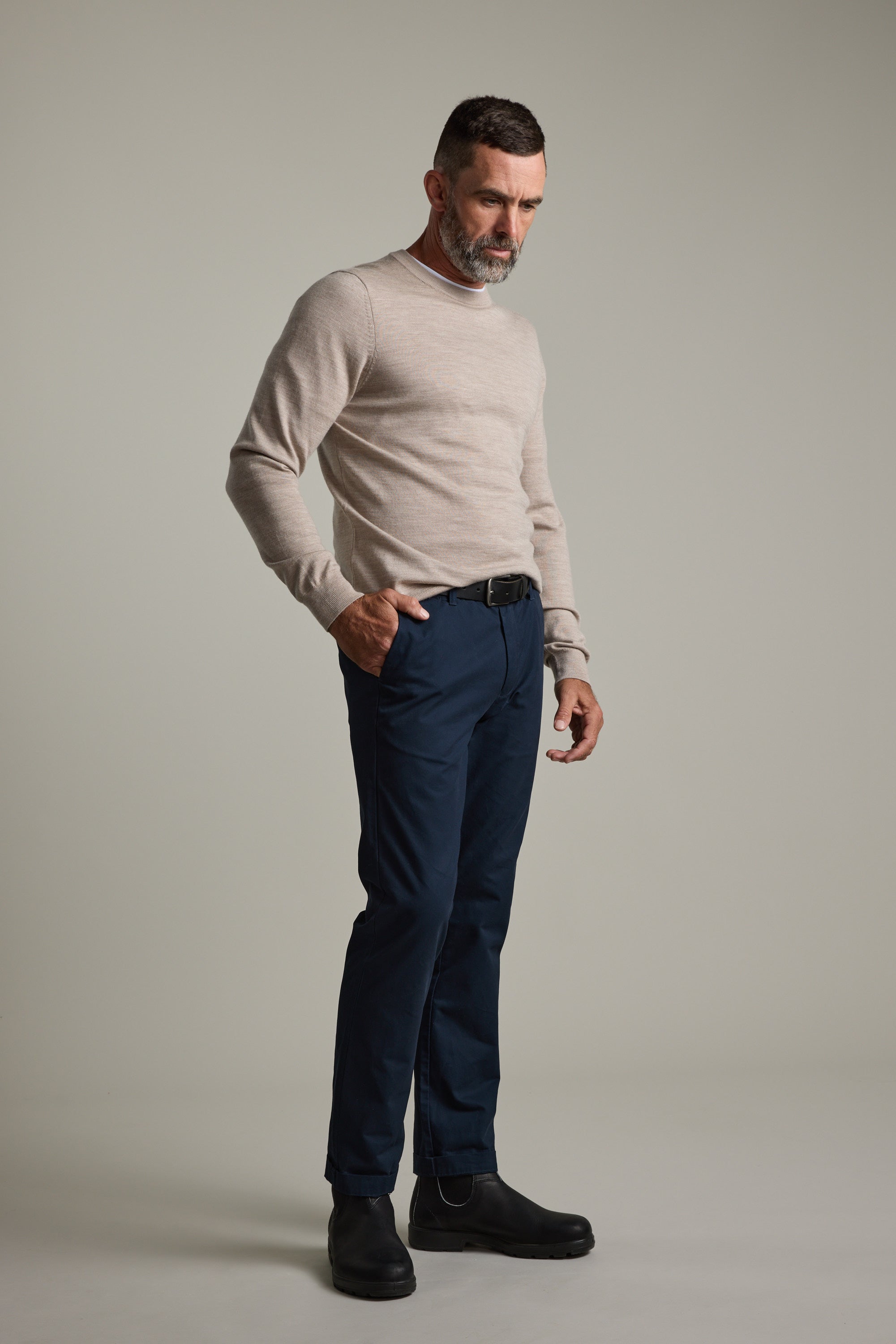 Man in beige Skyland ZQrx Merino Crew by Barkers and navy pants against a plain gray background.