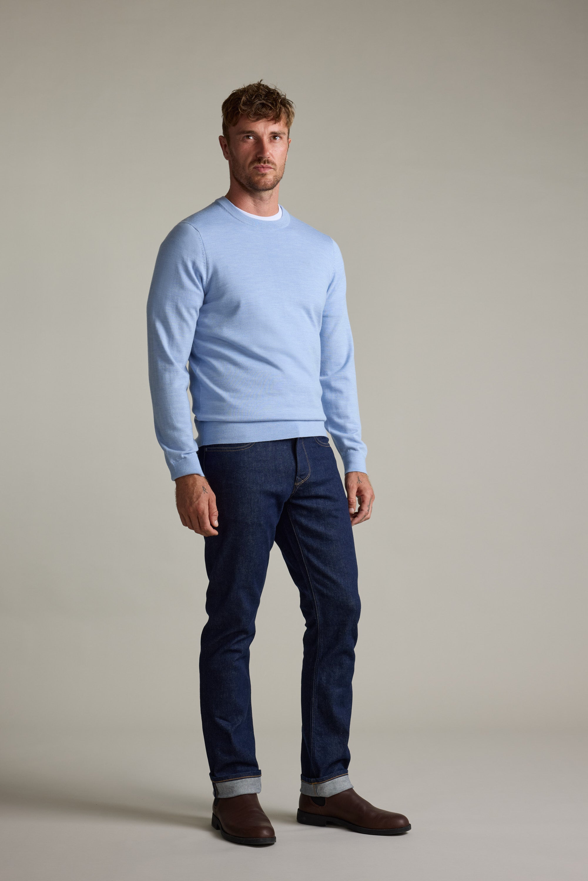 Man wears Barkers Skyland ZQrx Merino Crew sweater, dark jeans, and brown boots.