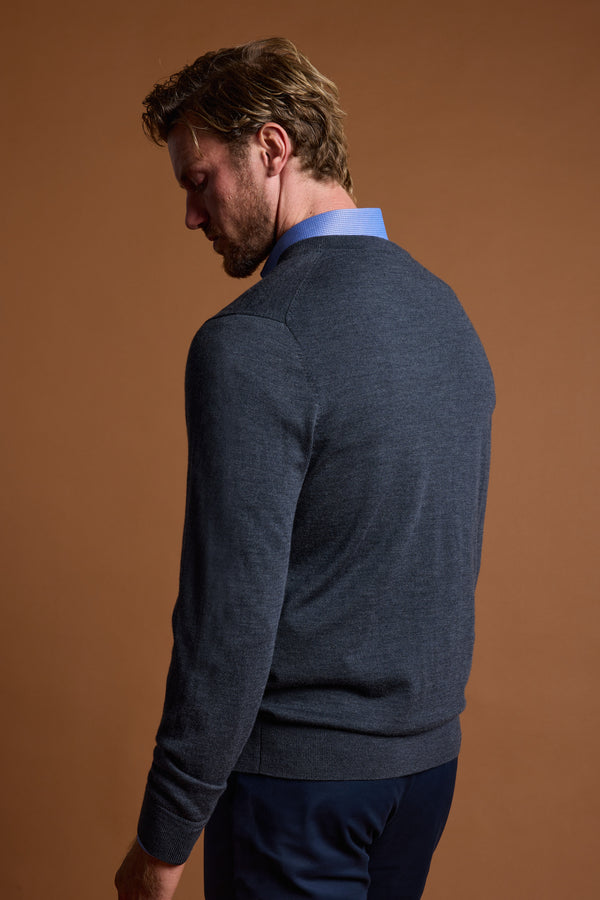 A man with light brown hair, facing away against a plain brown background, wears a blue collared shirt and the Barkers Skyland ZQrx Merino Vee dark gray sweater.