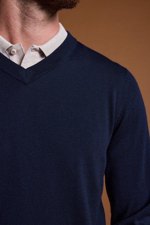 A close-up of a person wearing the Barkers Skyland ZQrx Merino Vee, a navy blue V-neck sweater made from breathable New Zealand merino wool, layered over a light beige collared shirt. The person's face is not visible.