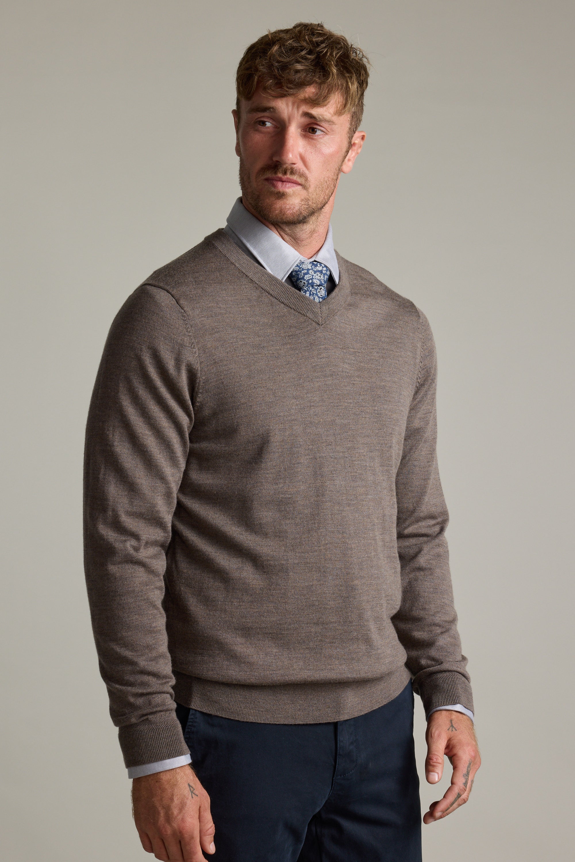 Man wearing the Barkers Skyland ZQrx Merino Vee sweater over a shirt and tie, plain background.