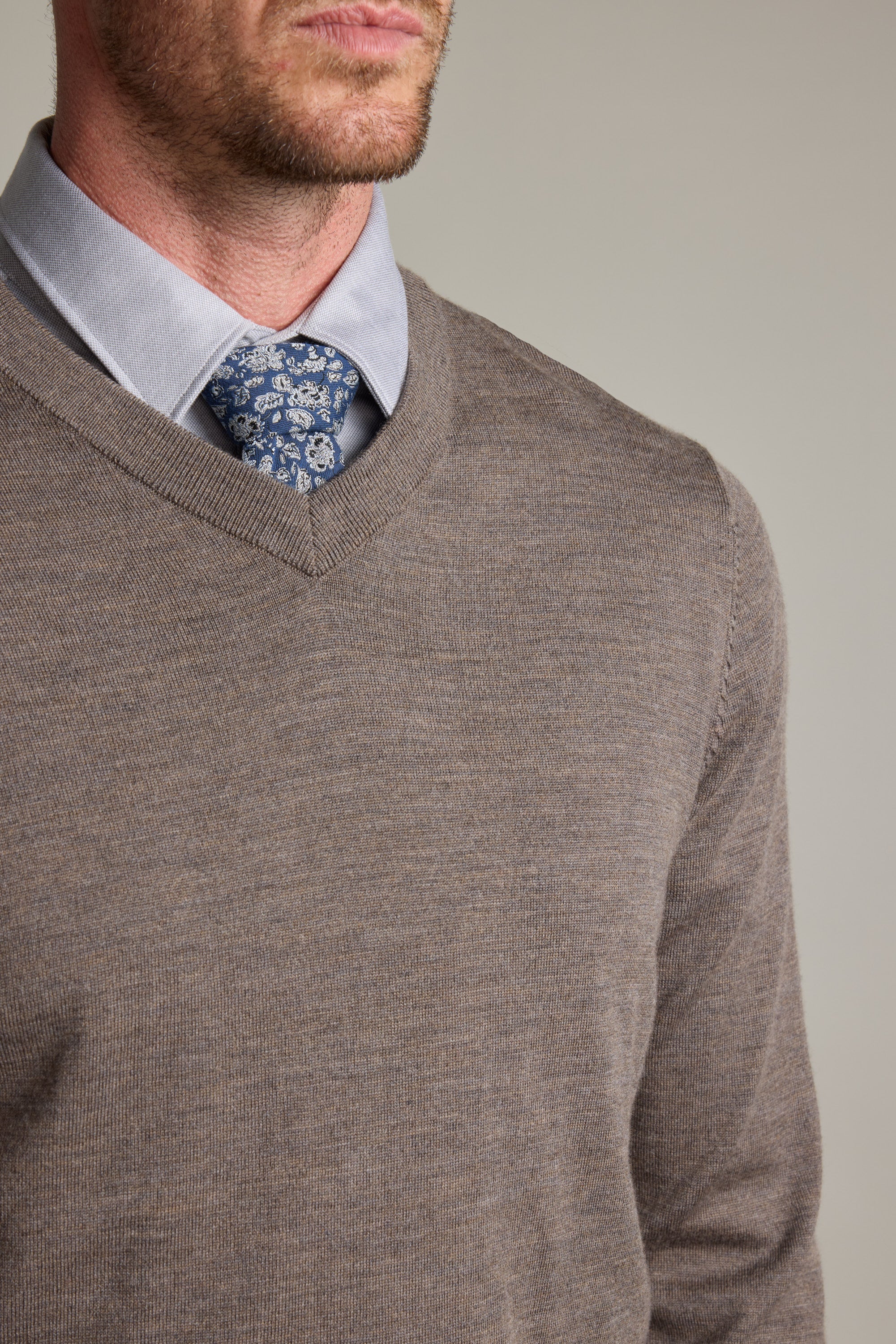 Man wearing Barkers Skyland ZQrx Merino Vee sweater, blue shirt, and floral tie, shoulders up.
